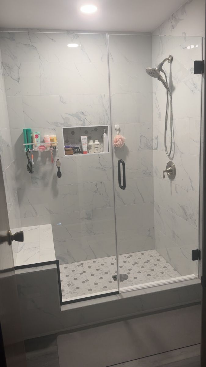 A bathroom with a walk in shower with a glass door.