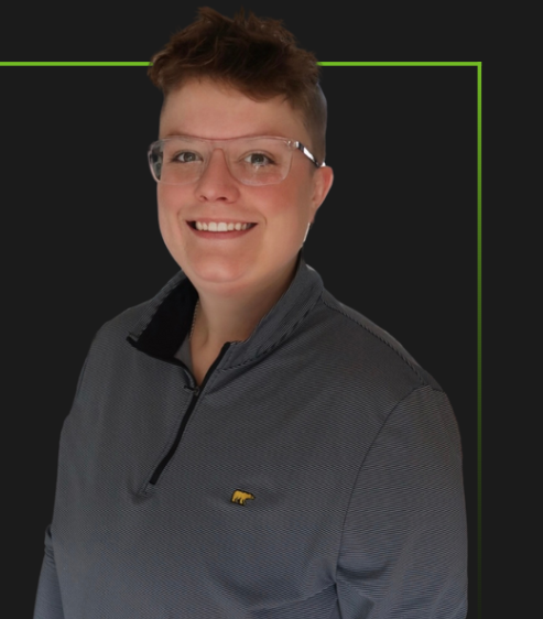A woman wearing glasses and a gray shirt is smiling for the camera.