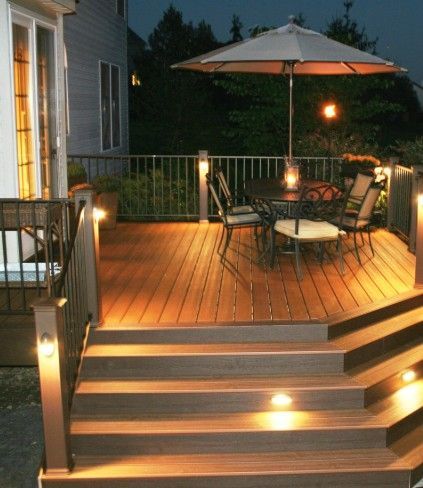 A deck with a table and chairs and an umbrella at night