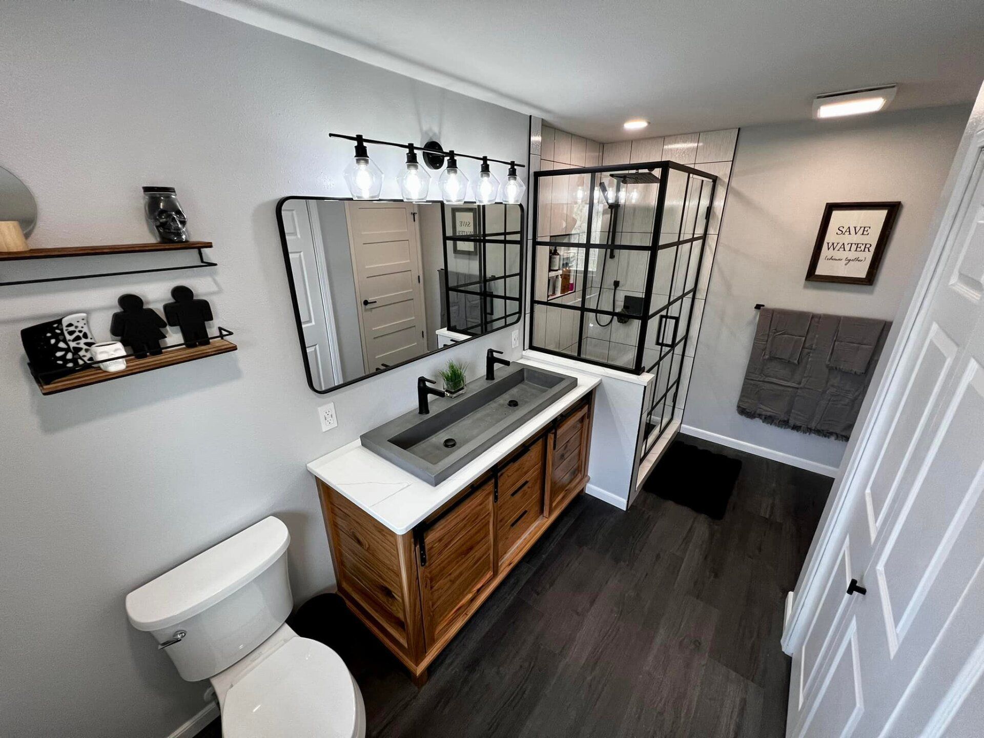 Modern bathroom with gray walls, dark wood vanity, and a black framed shower.