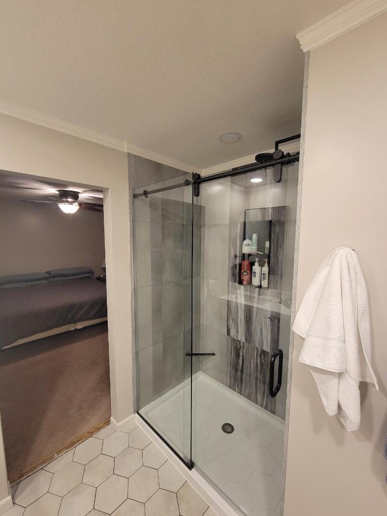 A bathroom with a sliding glass shower door and a towel hanging on the wall.