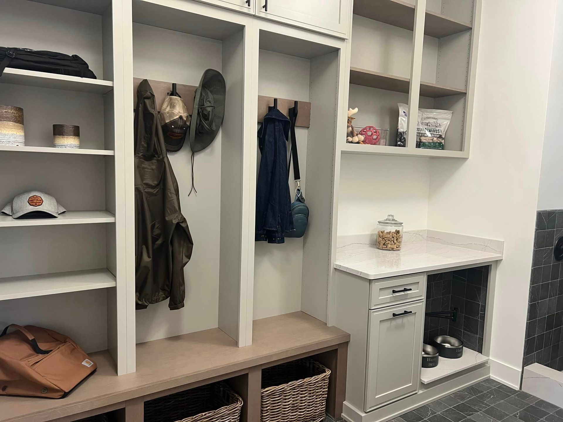 A mud room with a bench , shelves , and a dog bowl.