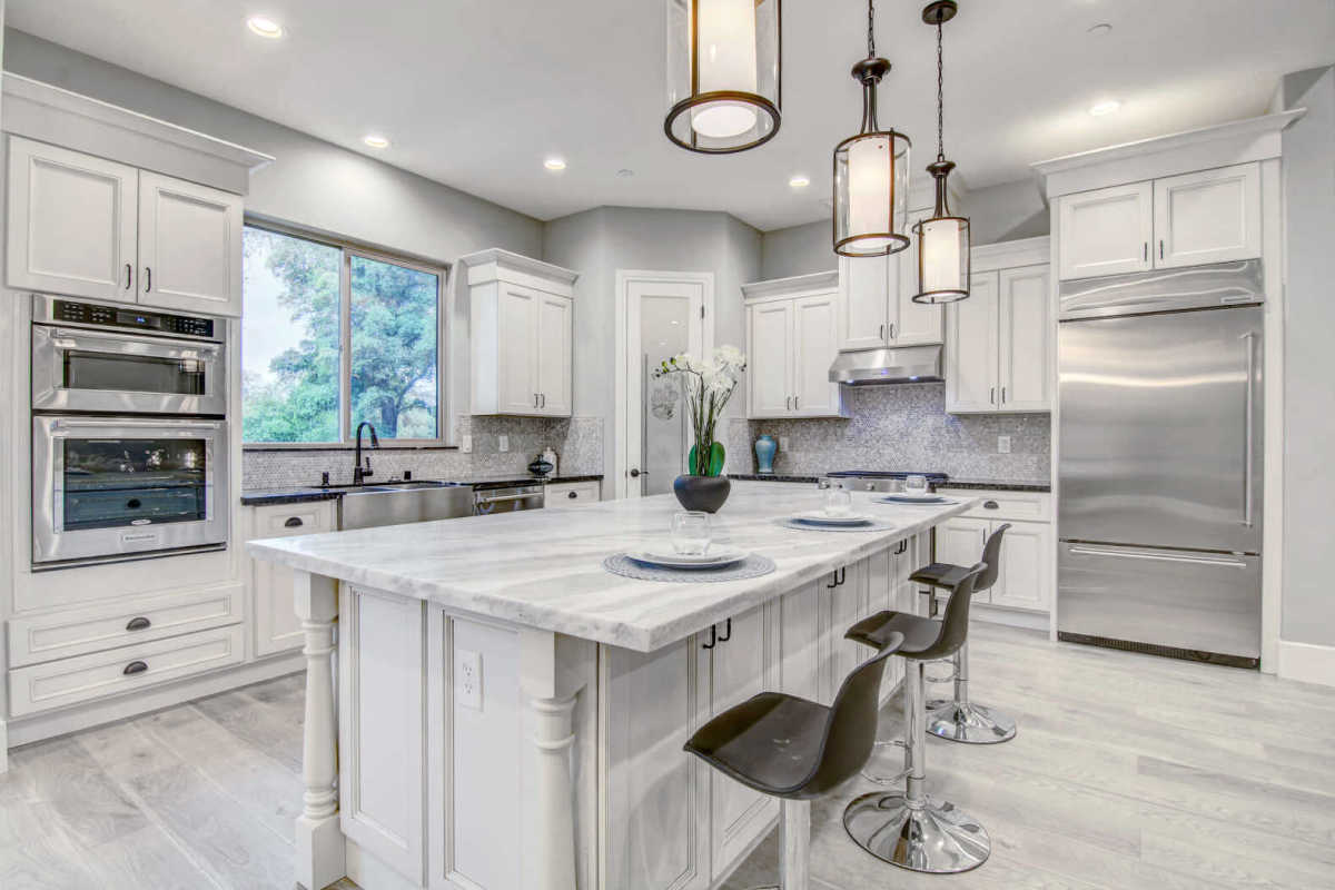A kitchen with white cabinets and stainless steel appliances and a large island.