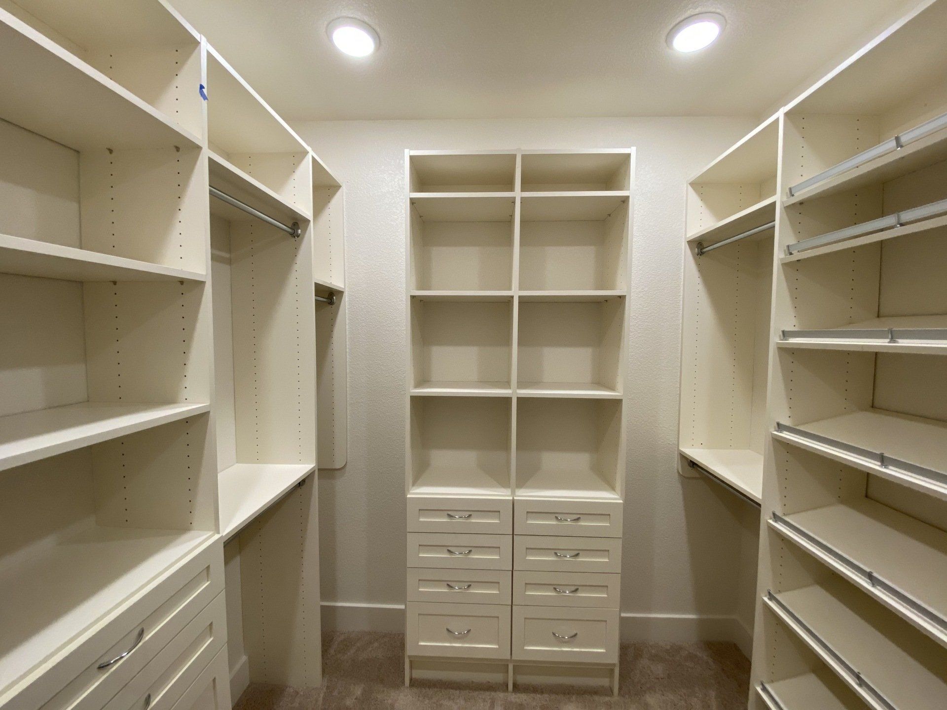 A walk in closet with lots of shelves and drawers