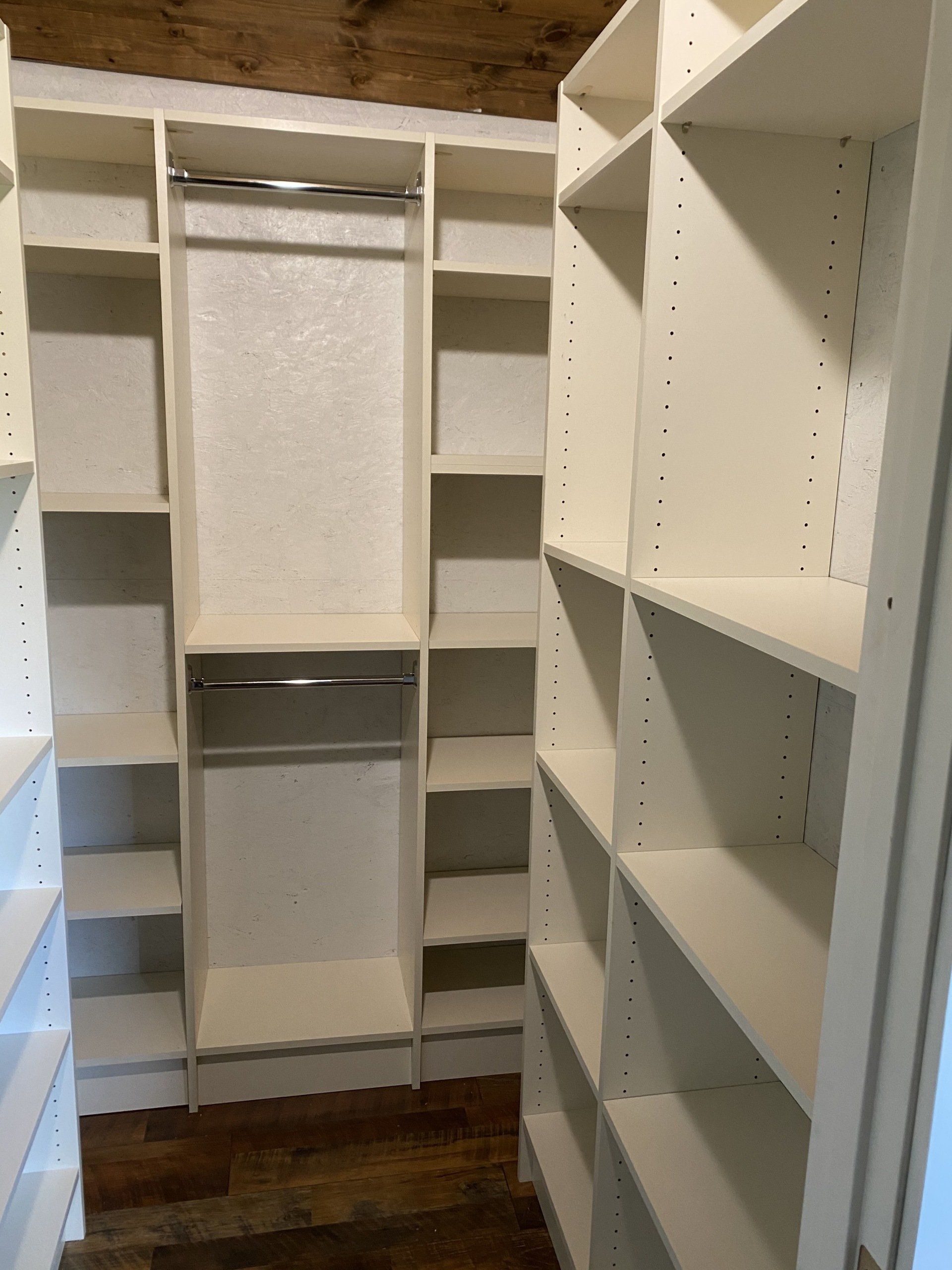 A walk in closet with lots of shelves and a hanging rack