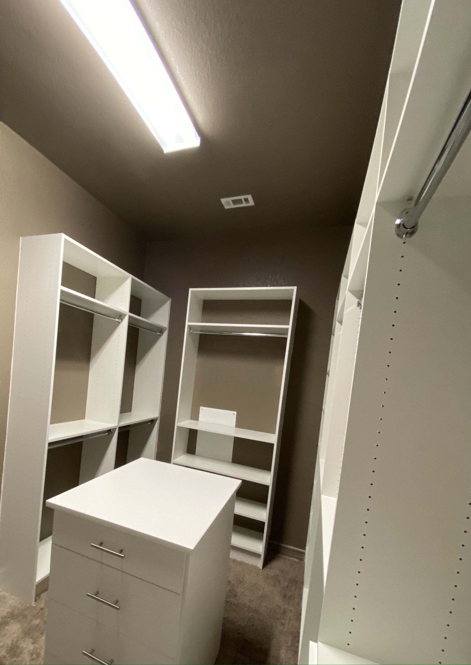 A walk in closet with lots of shelves and drawers