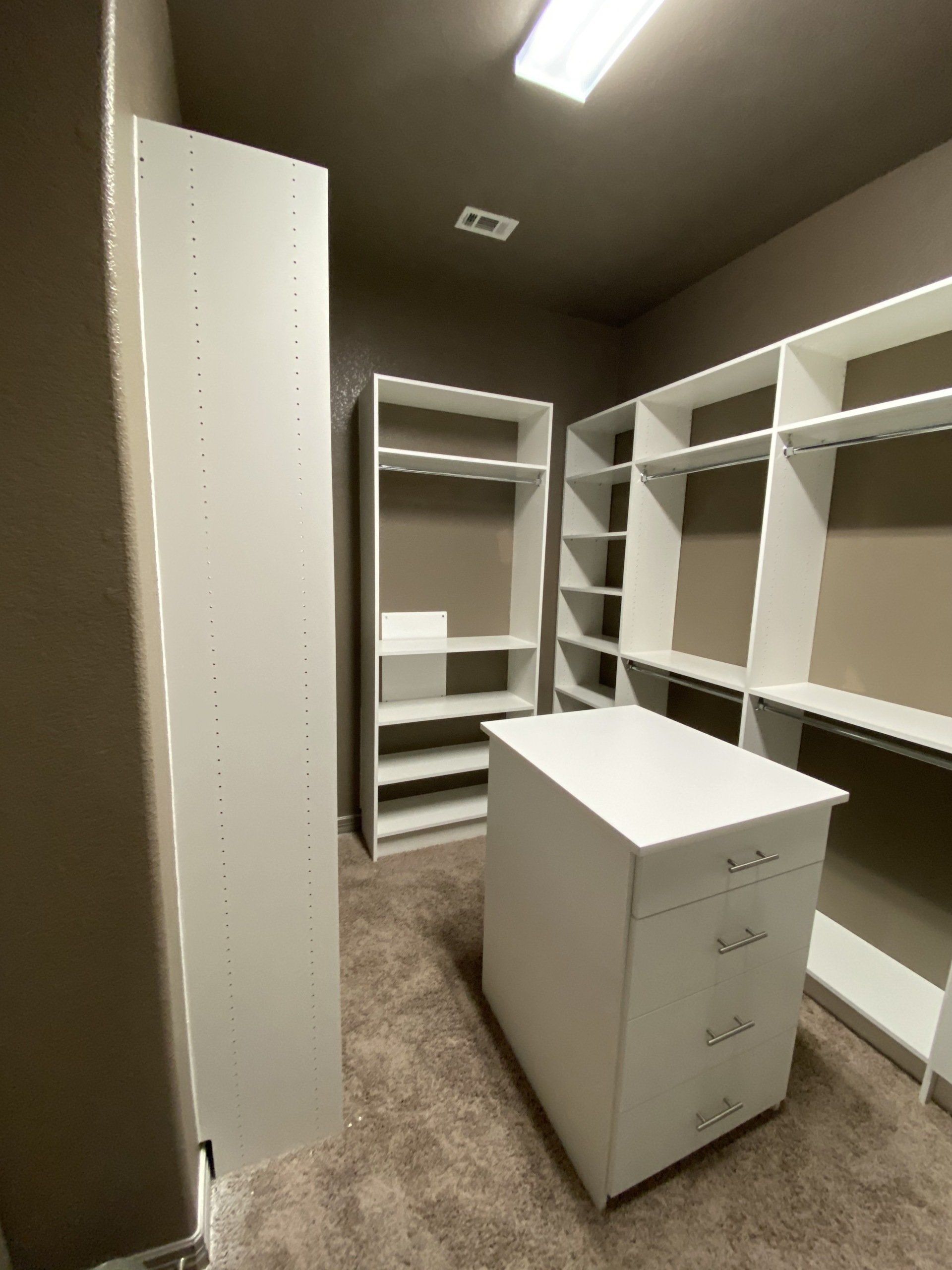 A walk in closet with lots of shelves and drawers.