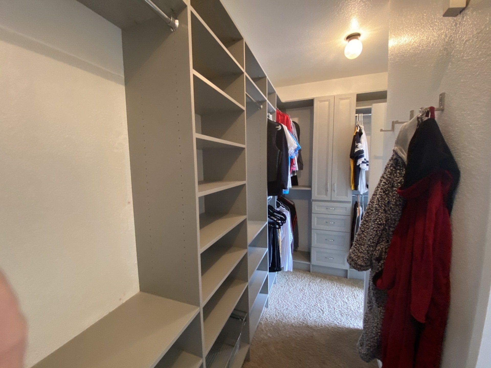 A walk in closet with lots of shelves and clothes hanging on the wall.