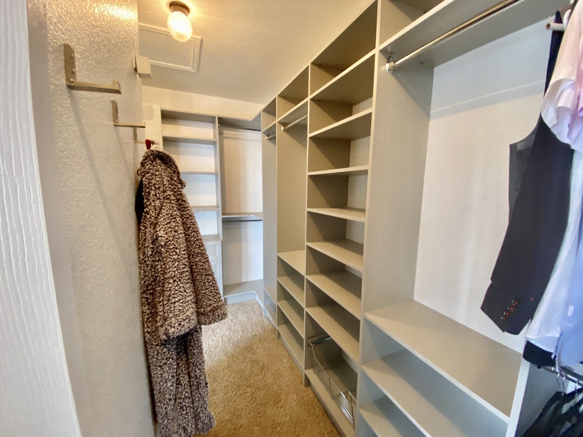 A walk in closet with a leopard print coat hanging on a hook.