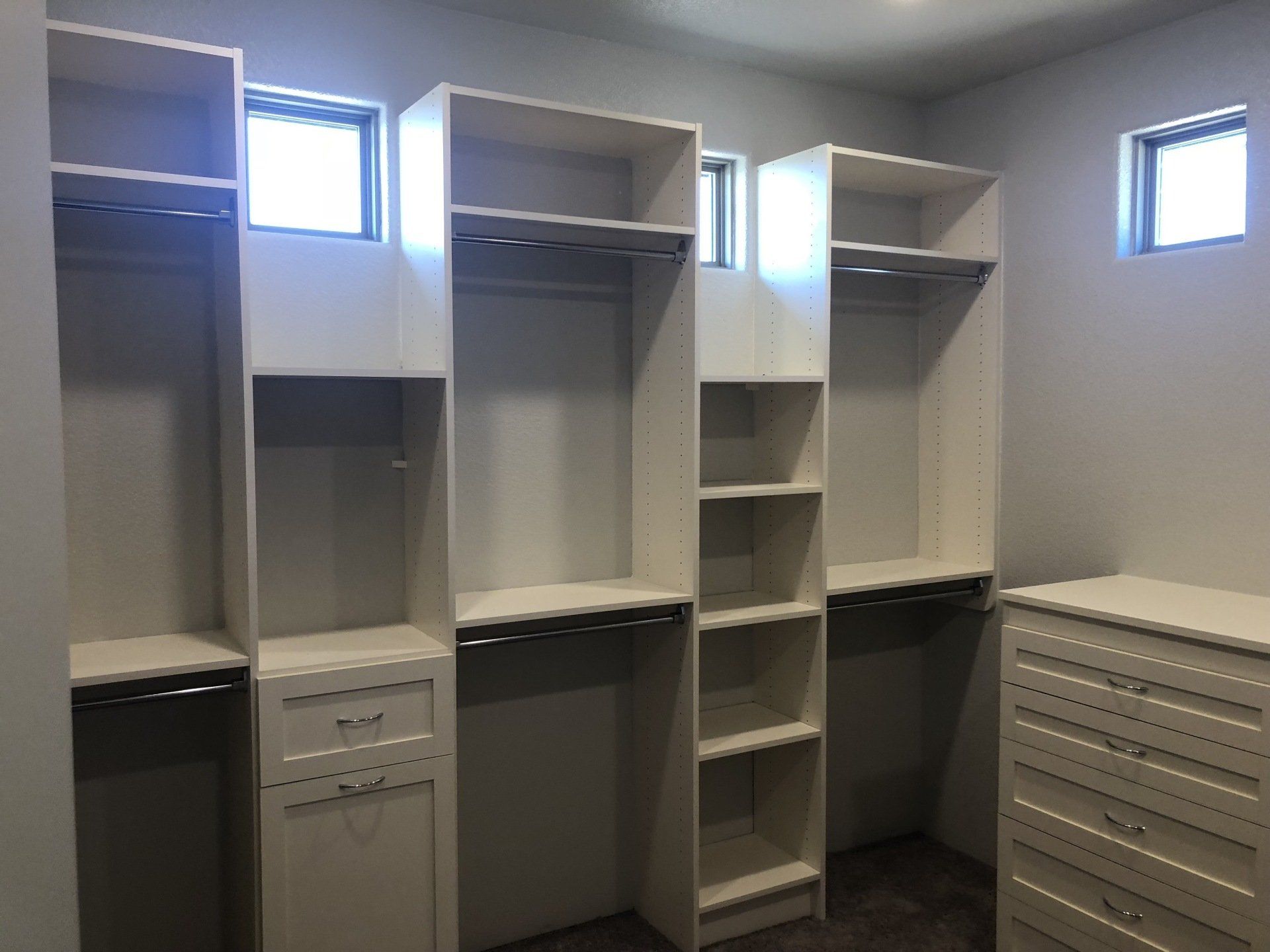 A walk in closet with lots of shelves and drawers