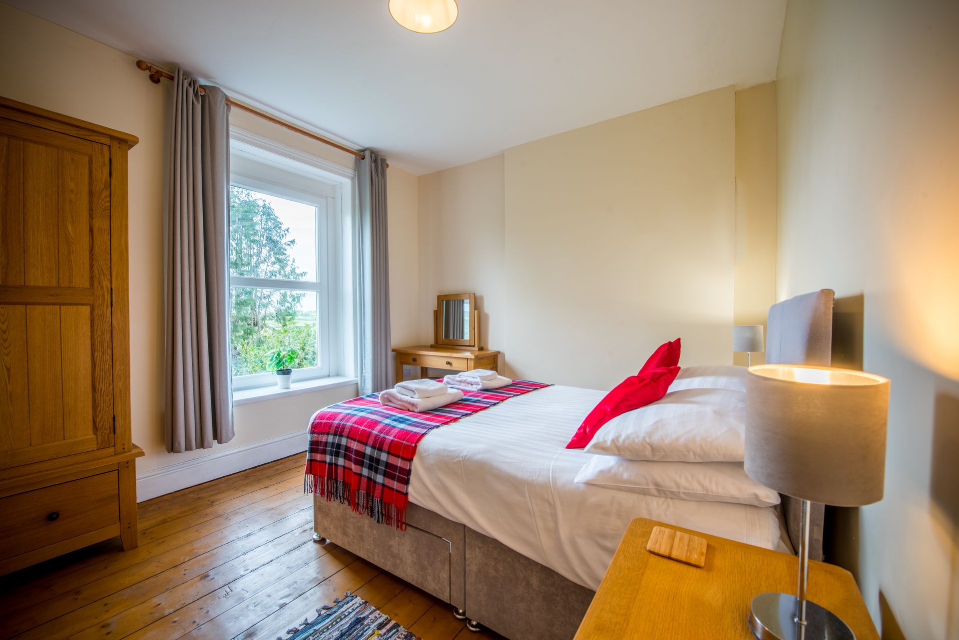 Double bedroom in The Farmhouse with red and white bedding and wooden furniture.