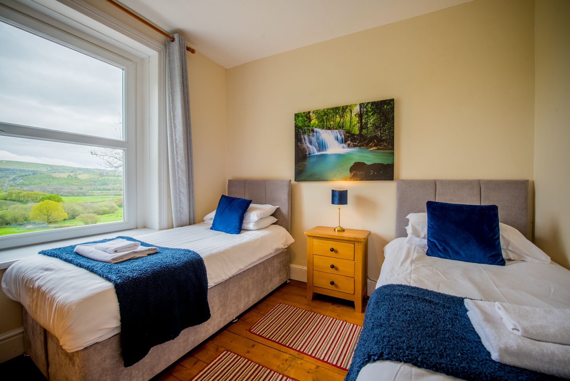 Twin bedroom at The Farmhouse with blue decor and garden views.