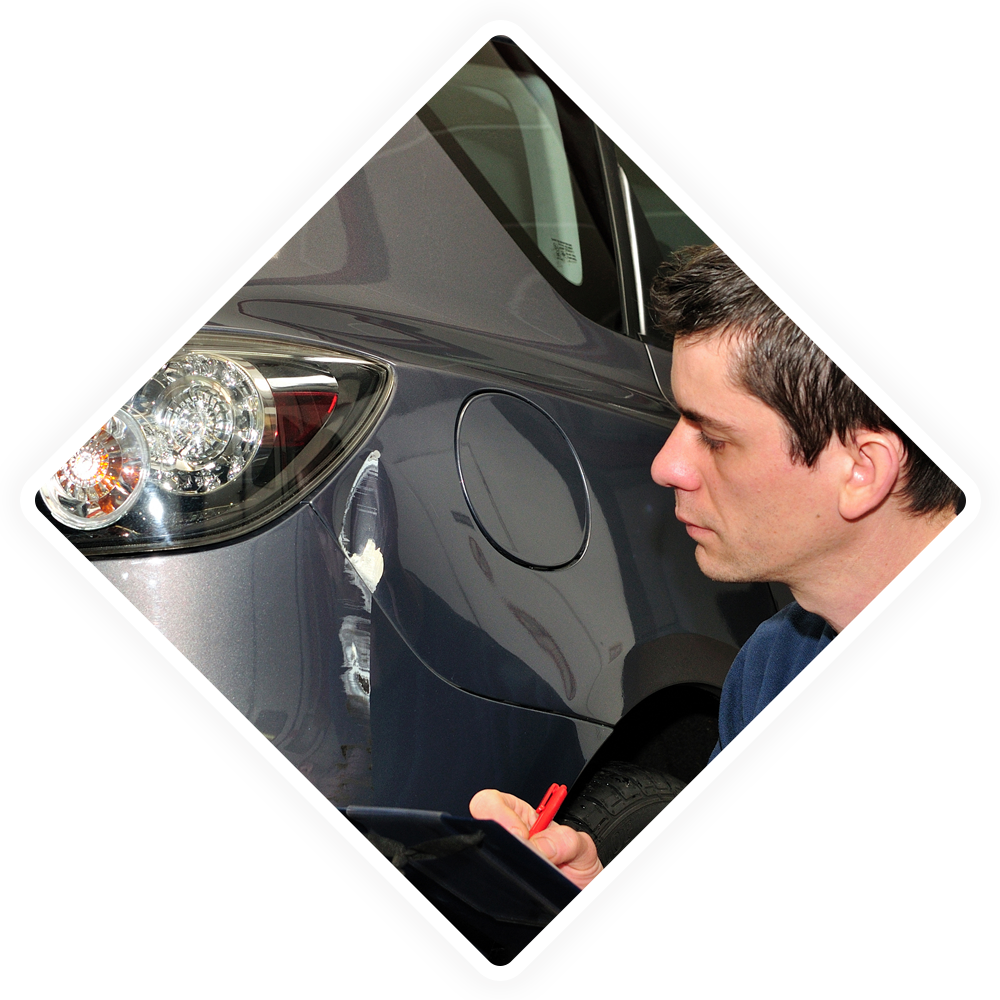 A man is writing on a piece of paper next to a car