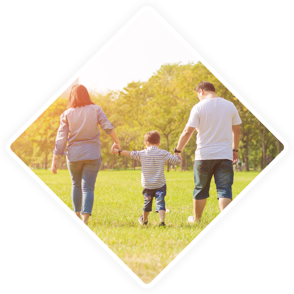 A family is walking through a grassy field holding hands.