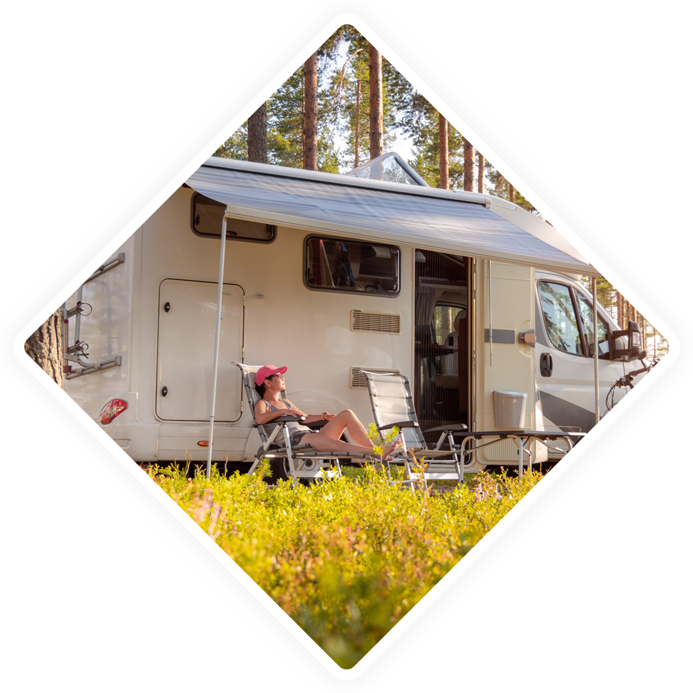 A woman is sitting in a chair outside of a rv.