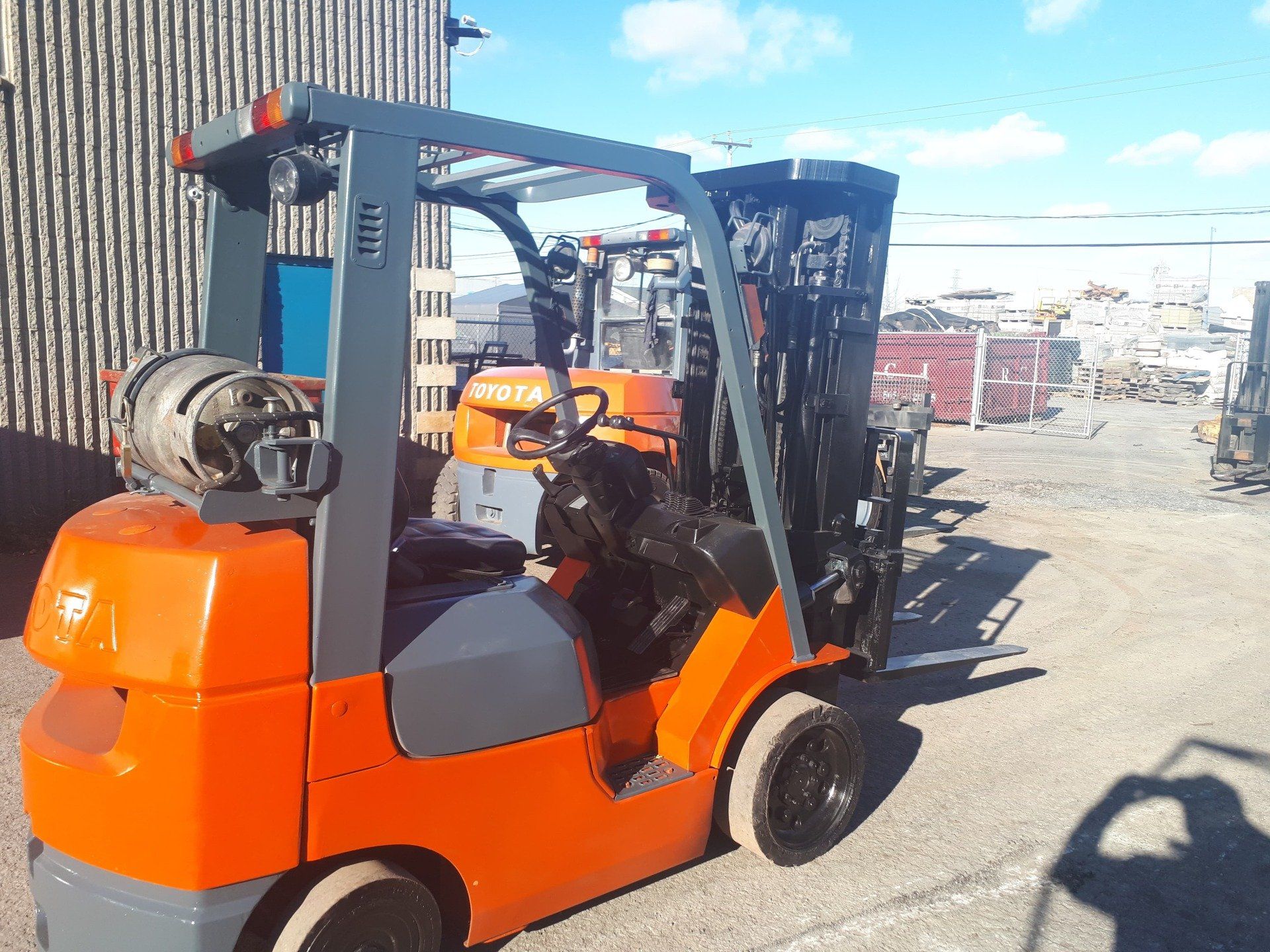 A forklift is parked in a parking lot in front of a building.
