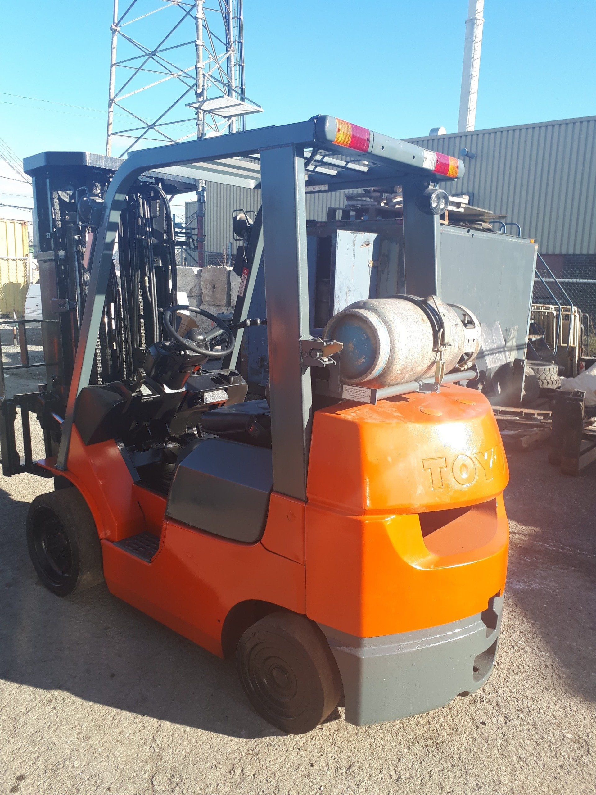 An orange forklift with a propane tank on top of it