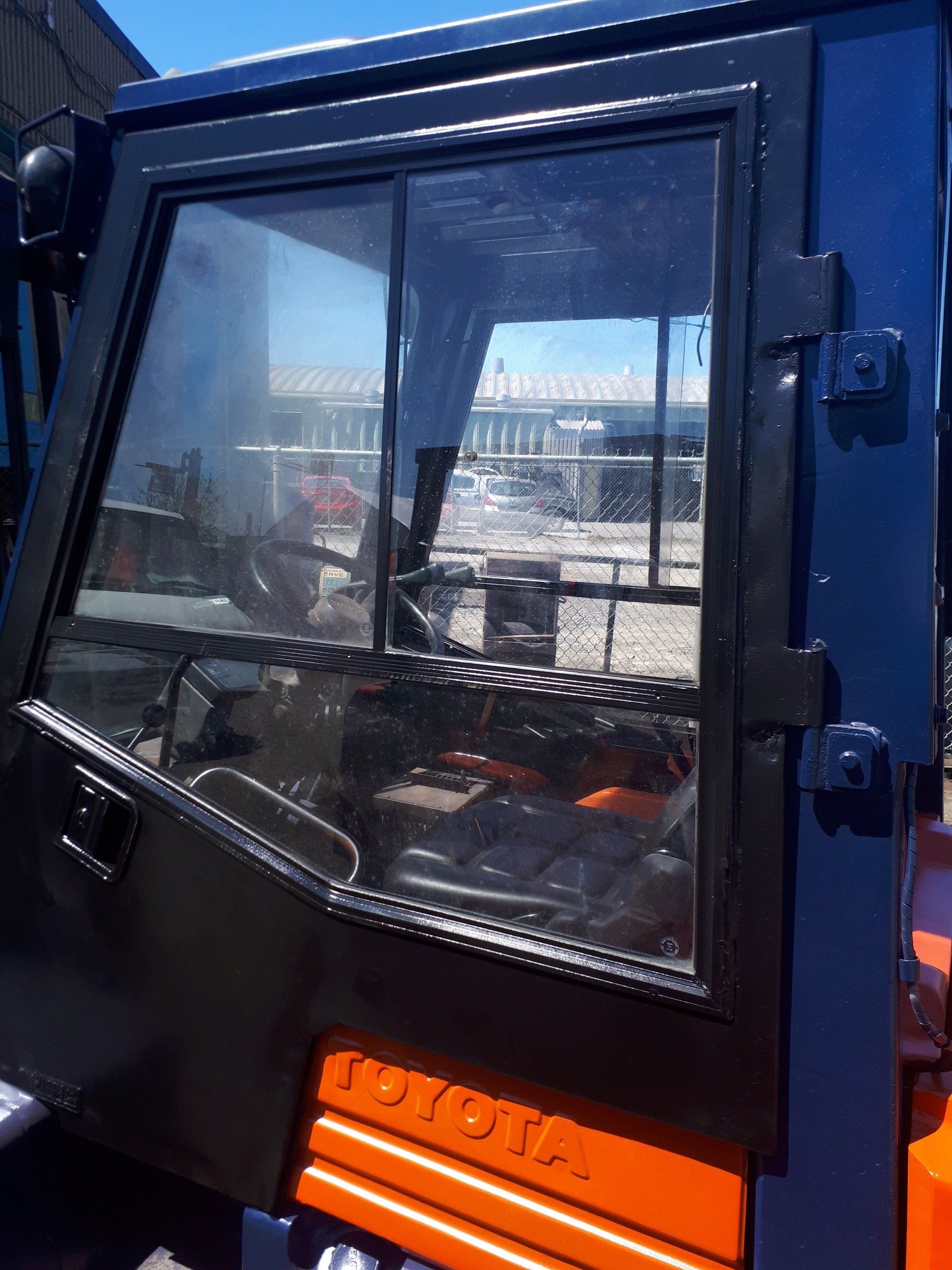 A blue and orange toyota forklift with the door open