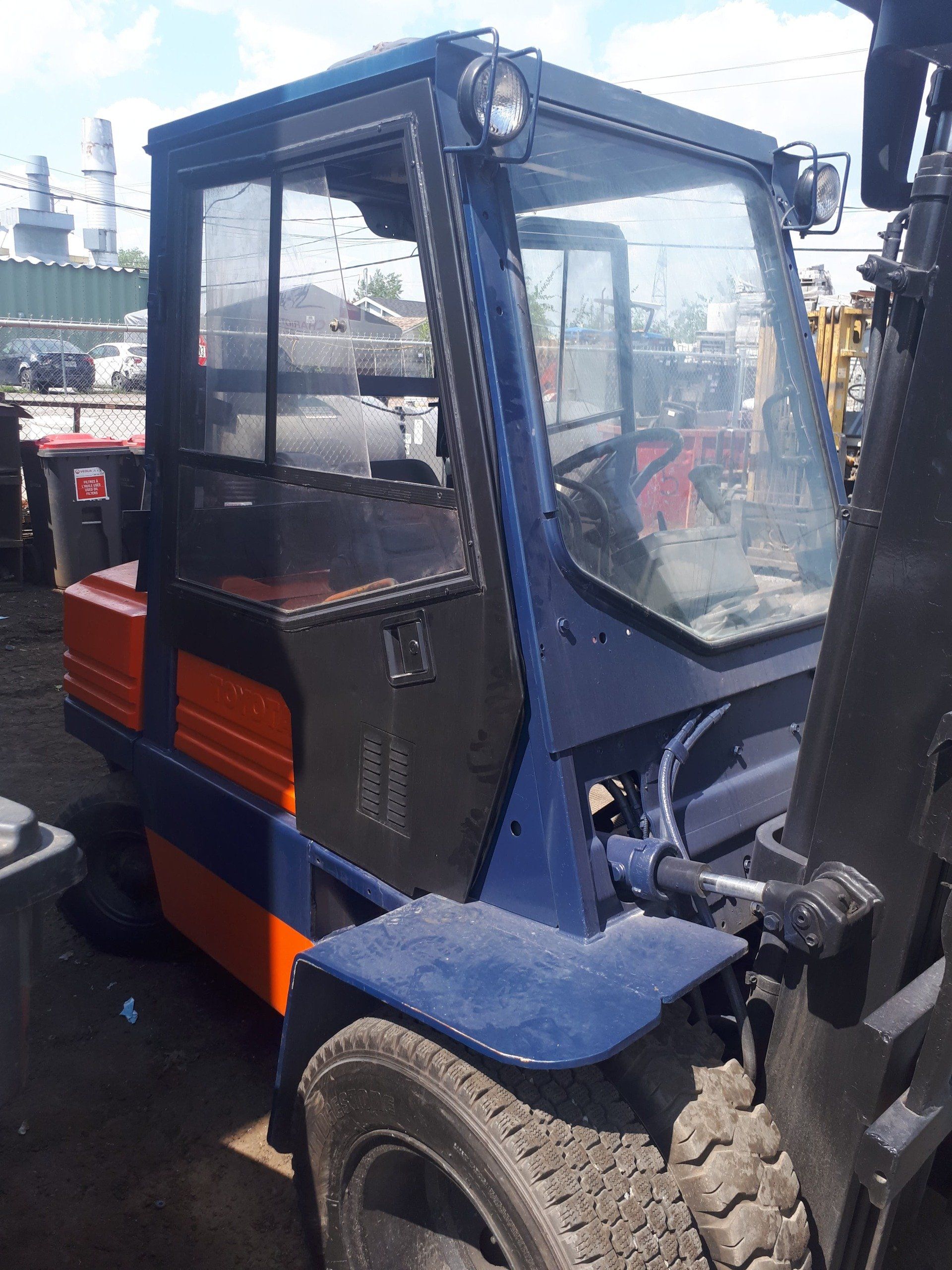 A blue and orange forklift is parked in a parking lot