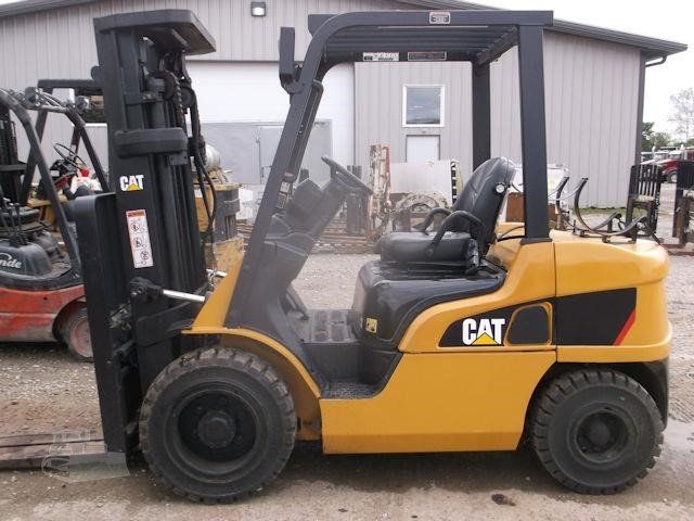 A yellow cat forklift is parked in front of a building