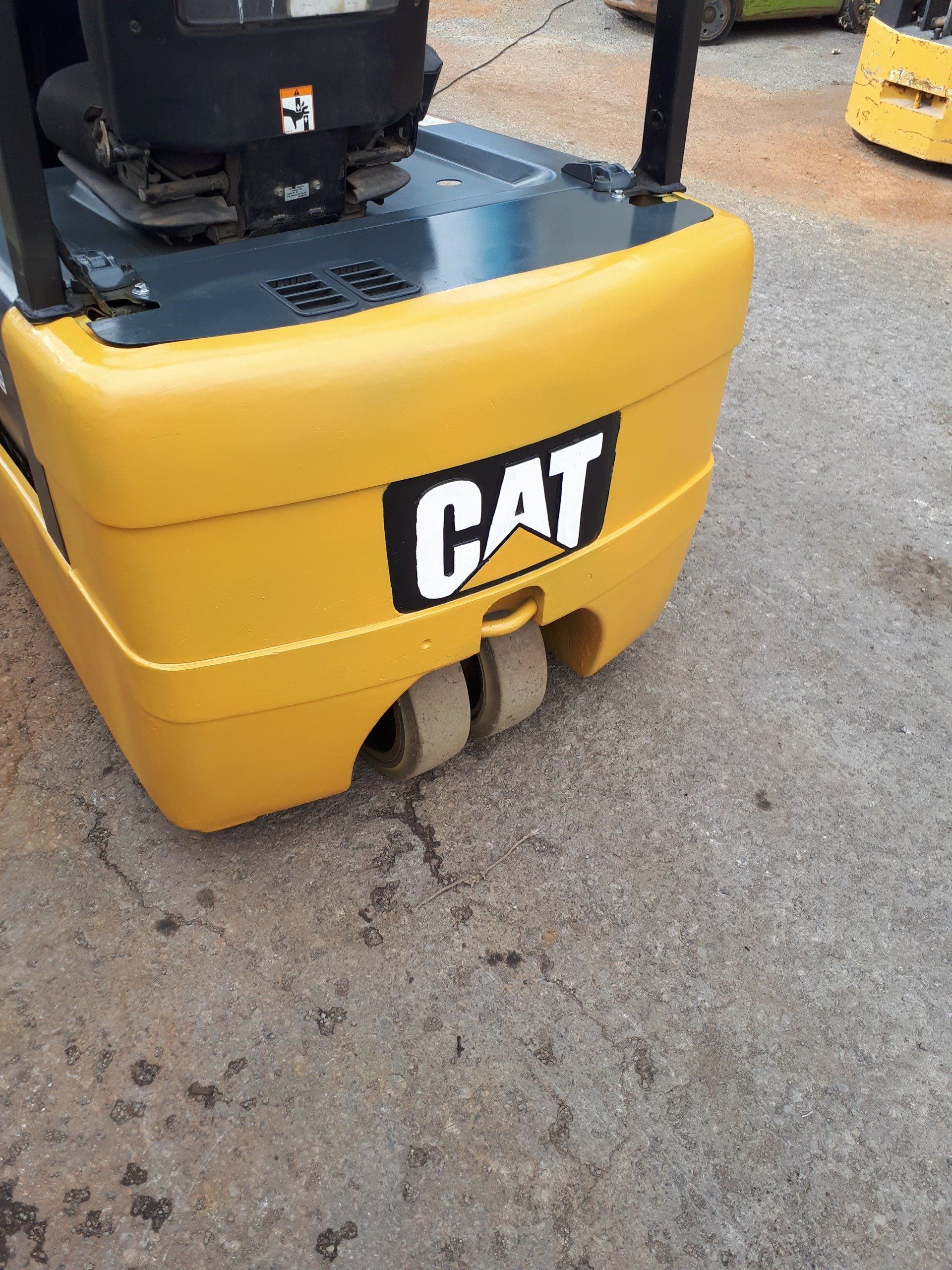 A yellow cat forklift is parked on the side of the road.