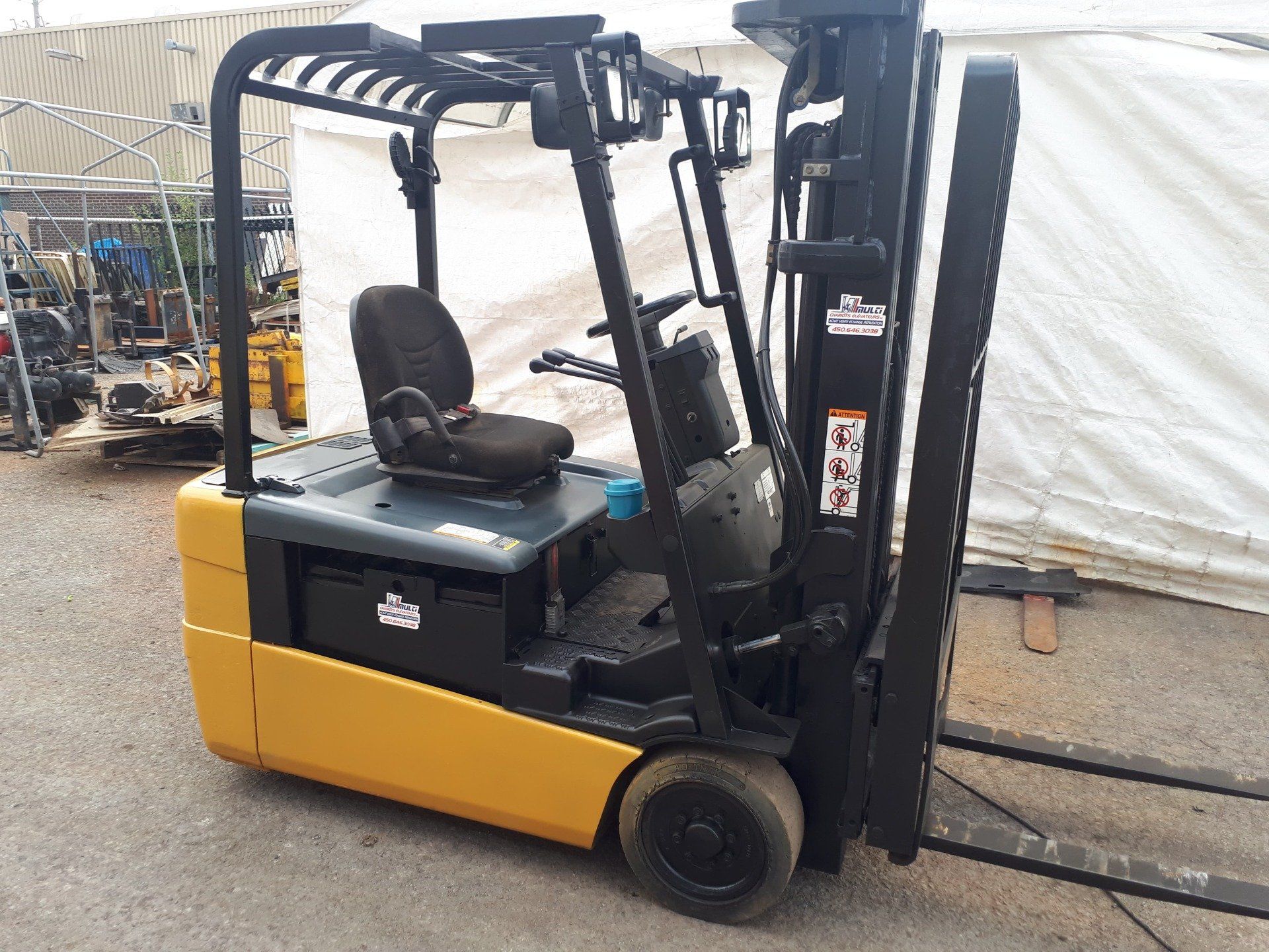 A yellow and black forklift is parked in front of a white tent.