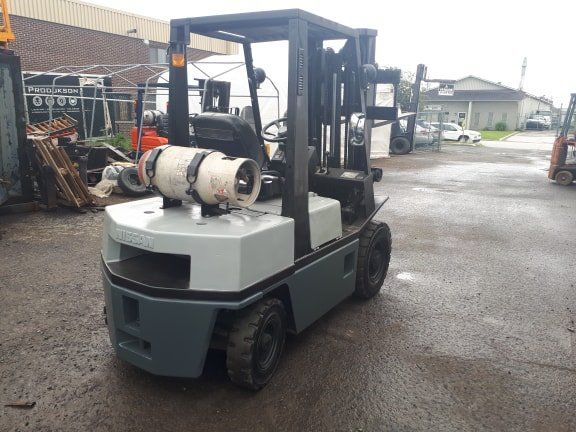 A forklift with a gas tank on the back is parked in a parking lot.