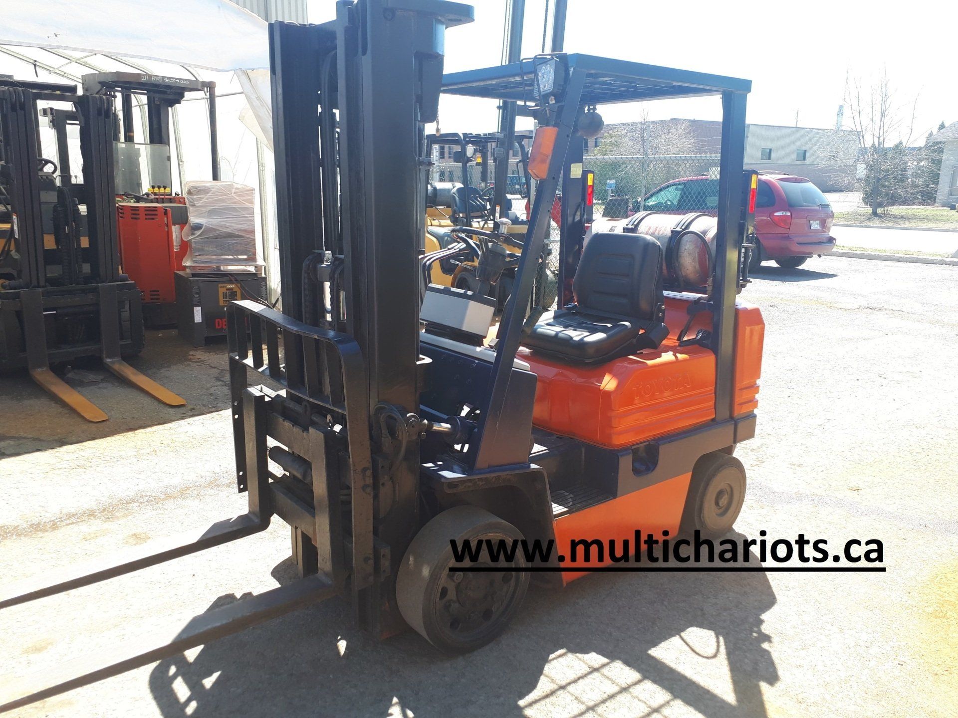 A forklift is parked in a parking lot and the website is www.multichariots.ca