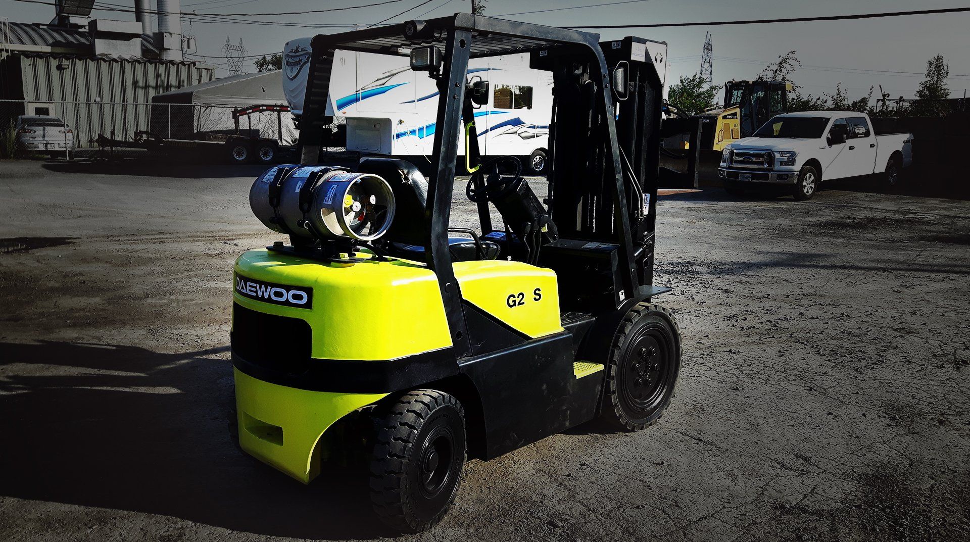 Chariot élévateur jaune et noir avec réservoirs de propane, stationné à l'extérieur.