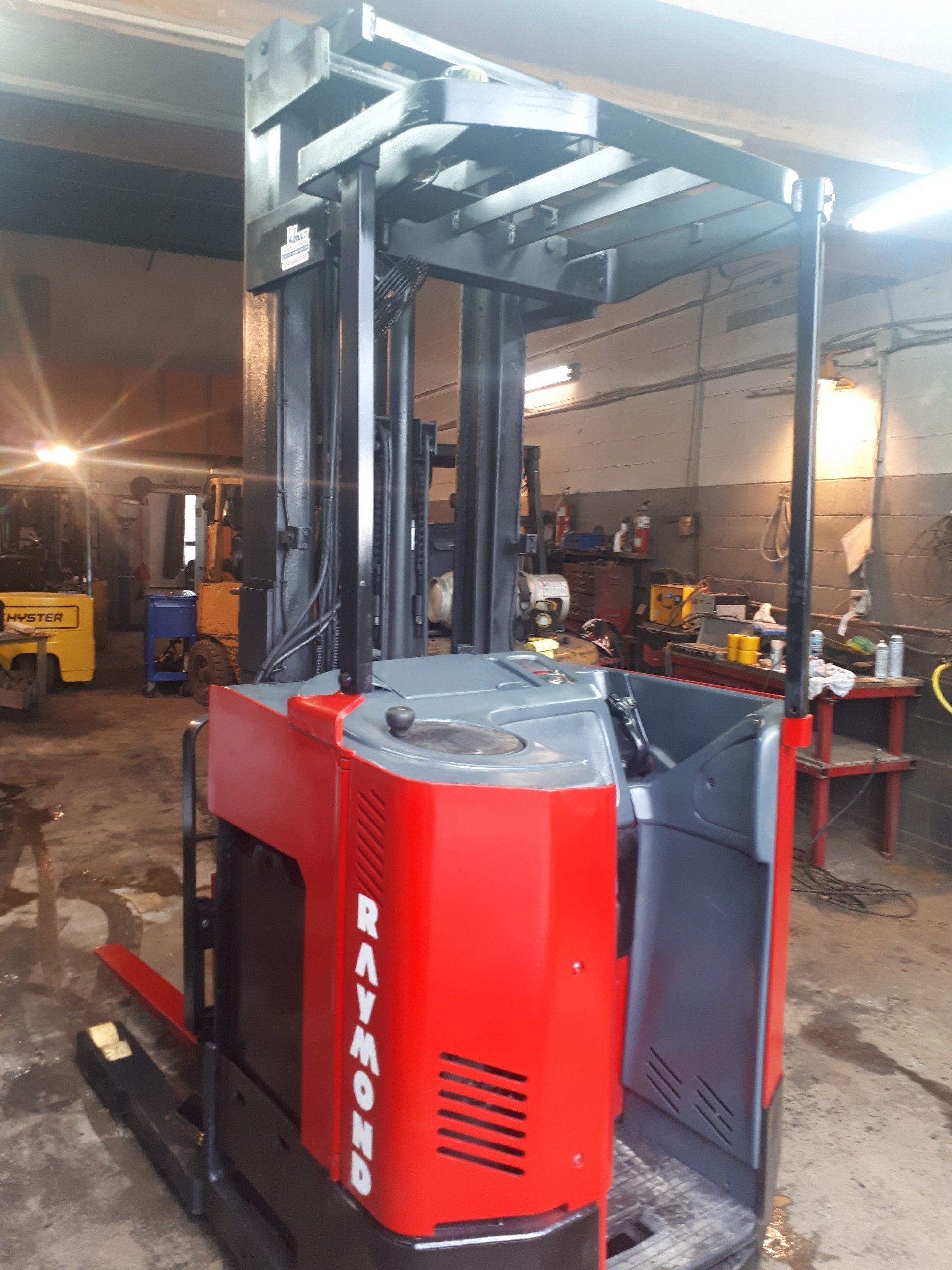A red and black forklift is parked in a garage