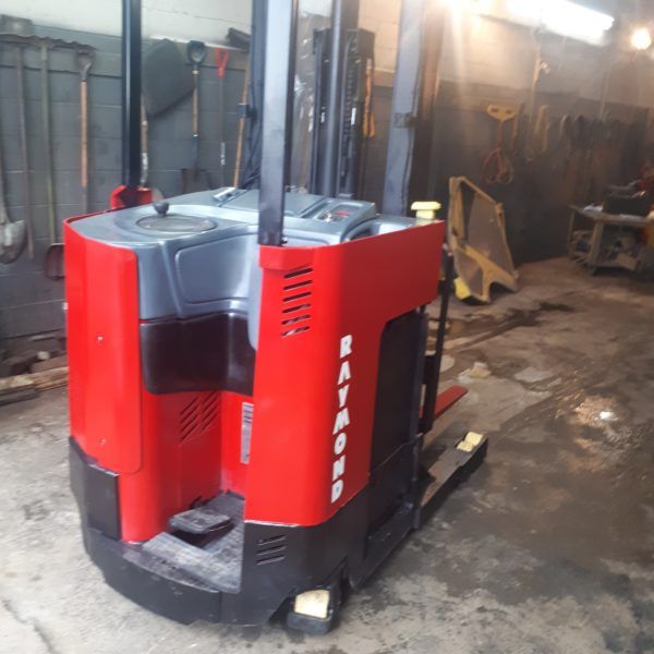 A red forklift in a garage with the word gator on the side