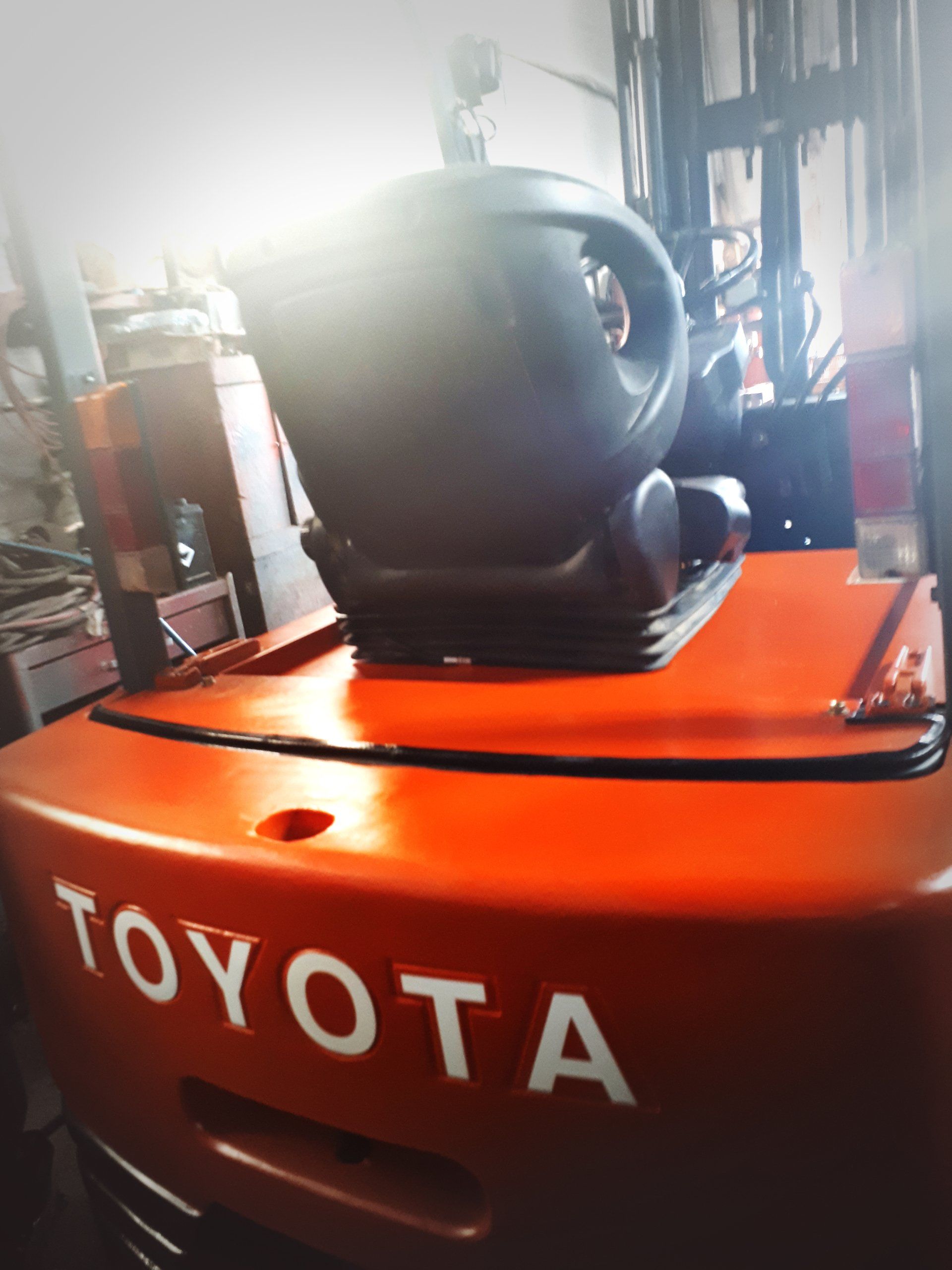 Chariot élévateur Toyota orange avec siège noir et logo à l'avant.