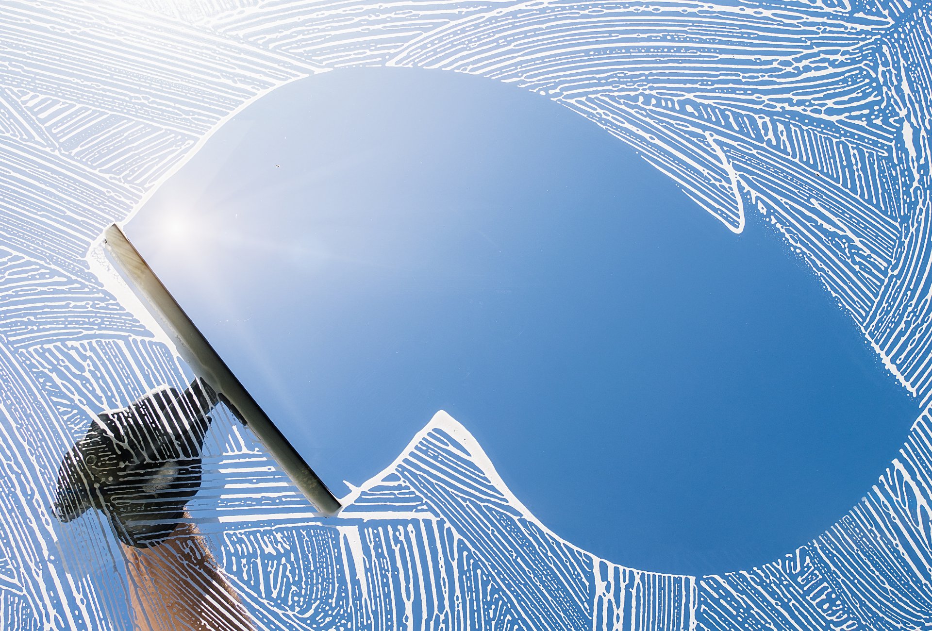 A person is cleaning a window with a squeegee.