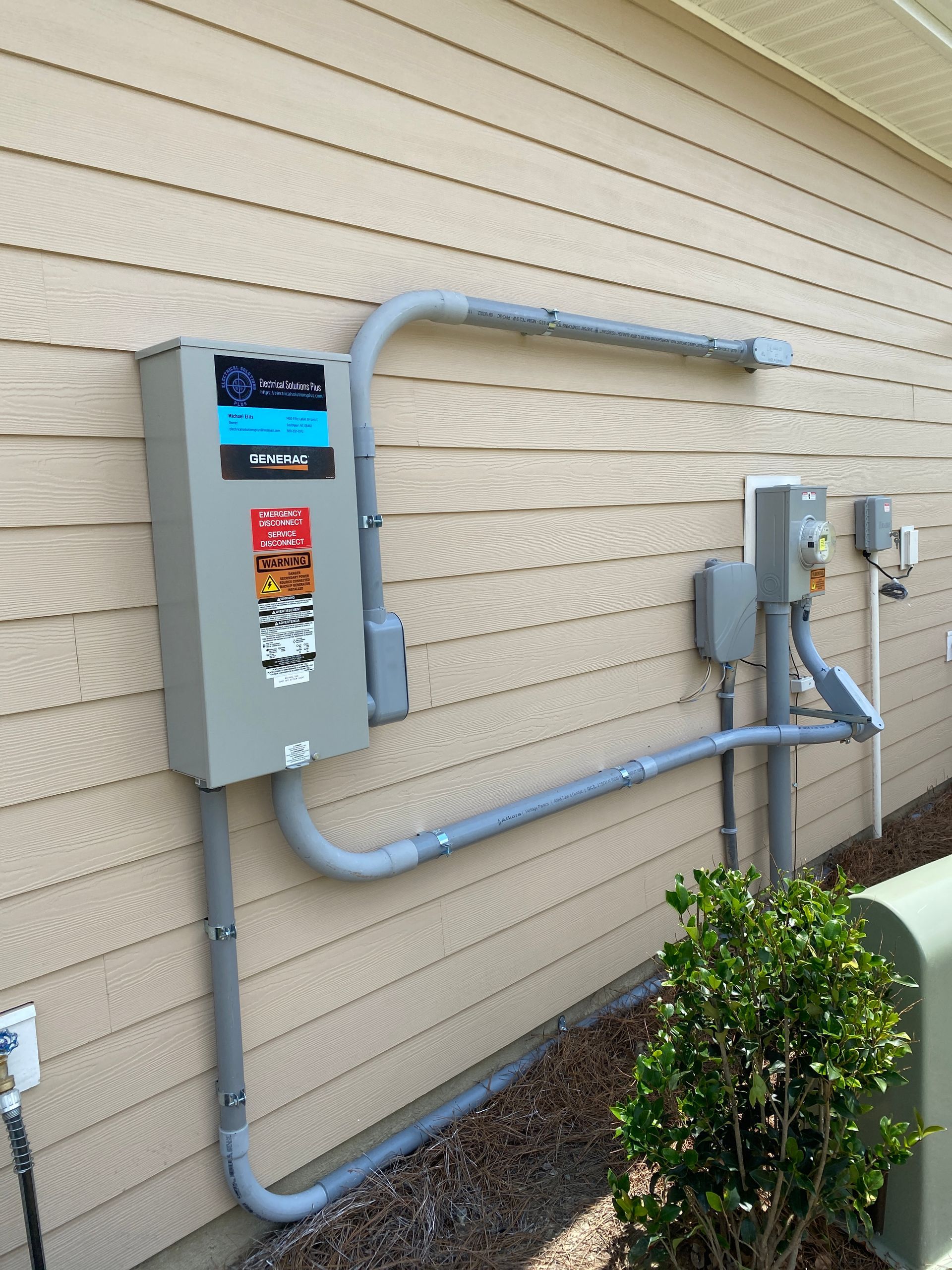 An electrical box is attached to the side of a house