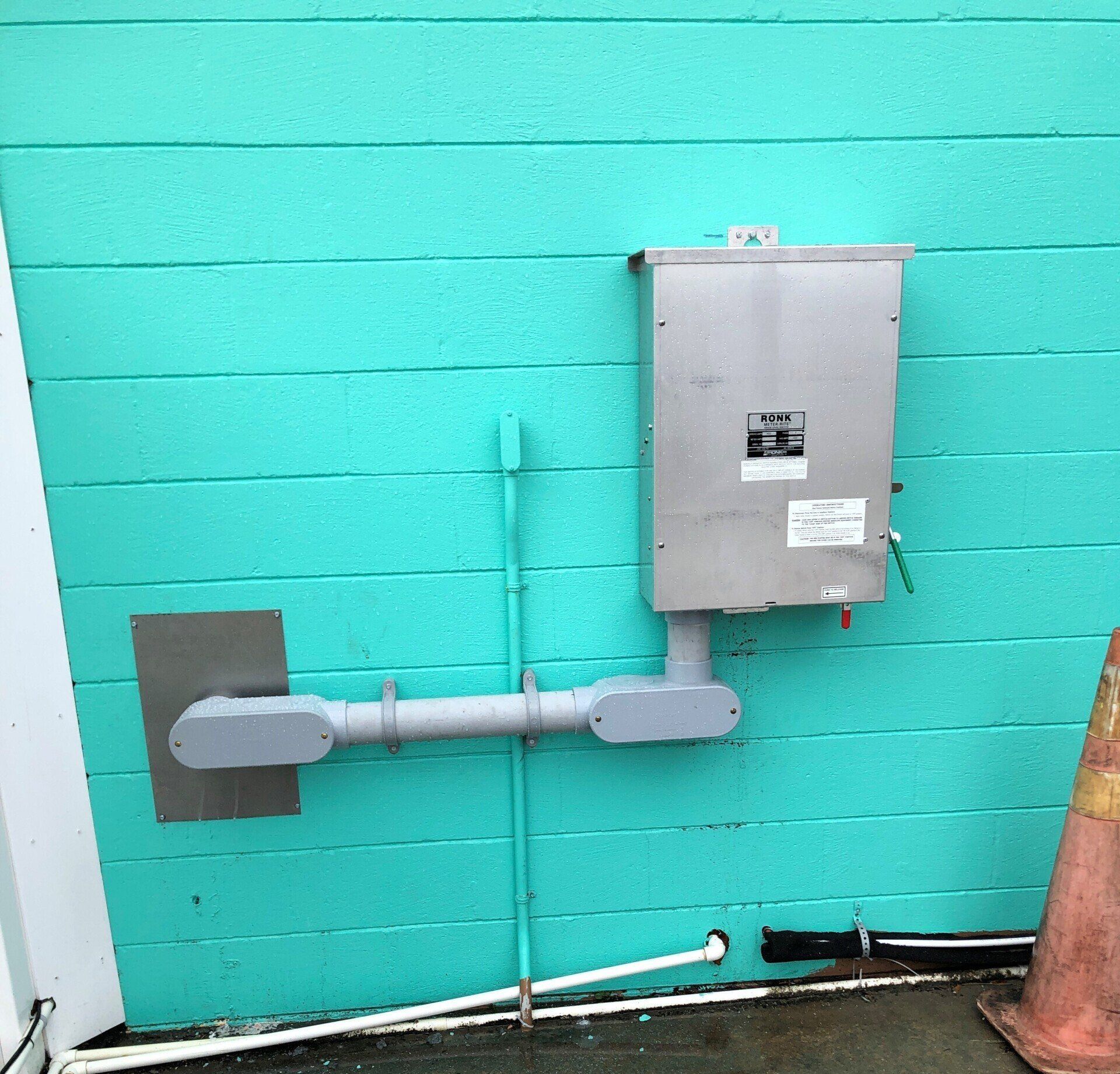 A turquoise wall with a stainless steel box on it