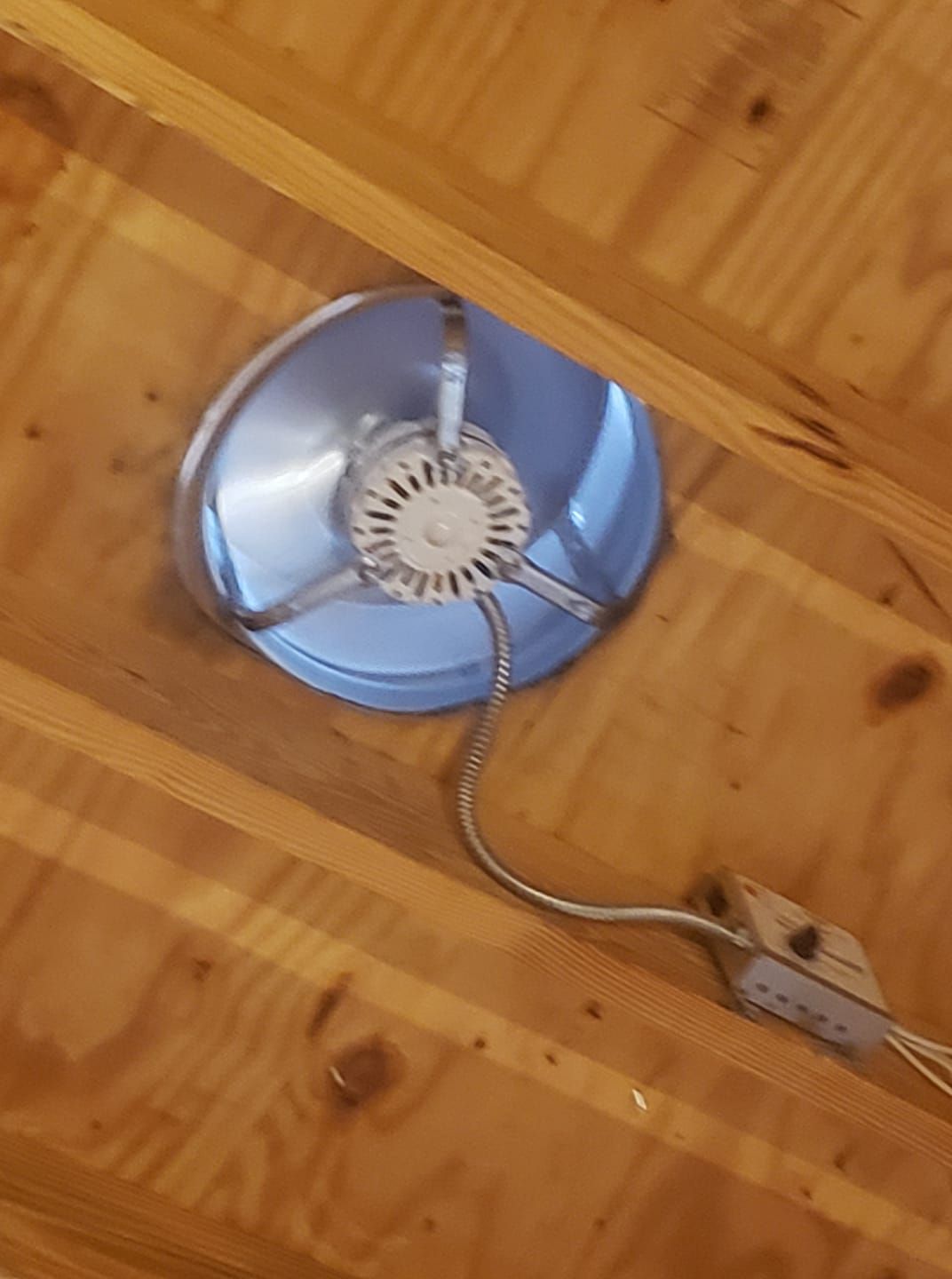 A fan is hanging from the ceiling of a wooden room