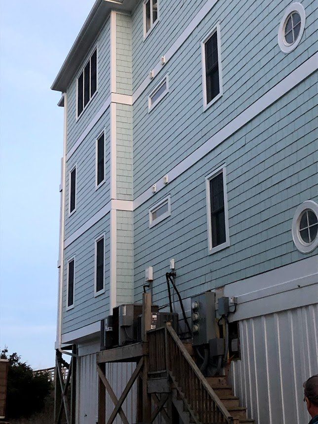 A man is standing in front of a large building with stairs leading up to it.