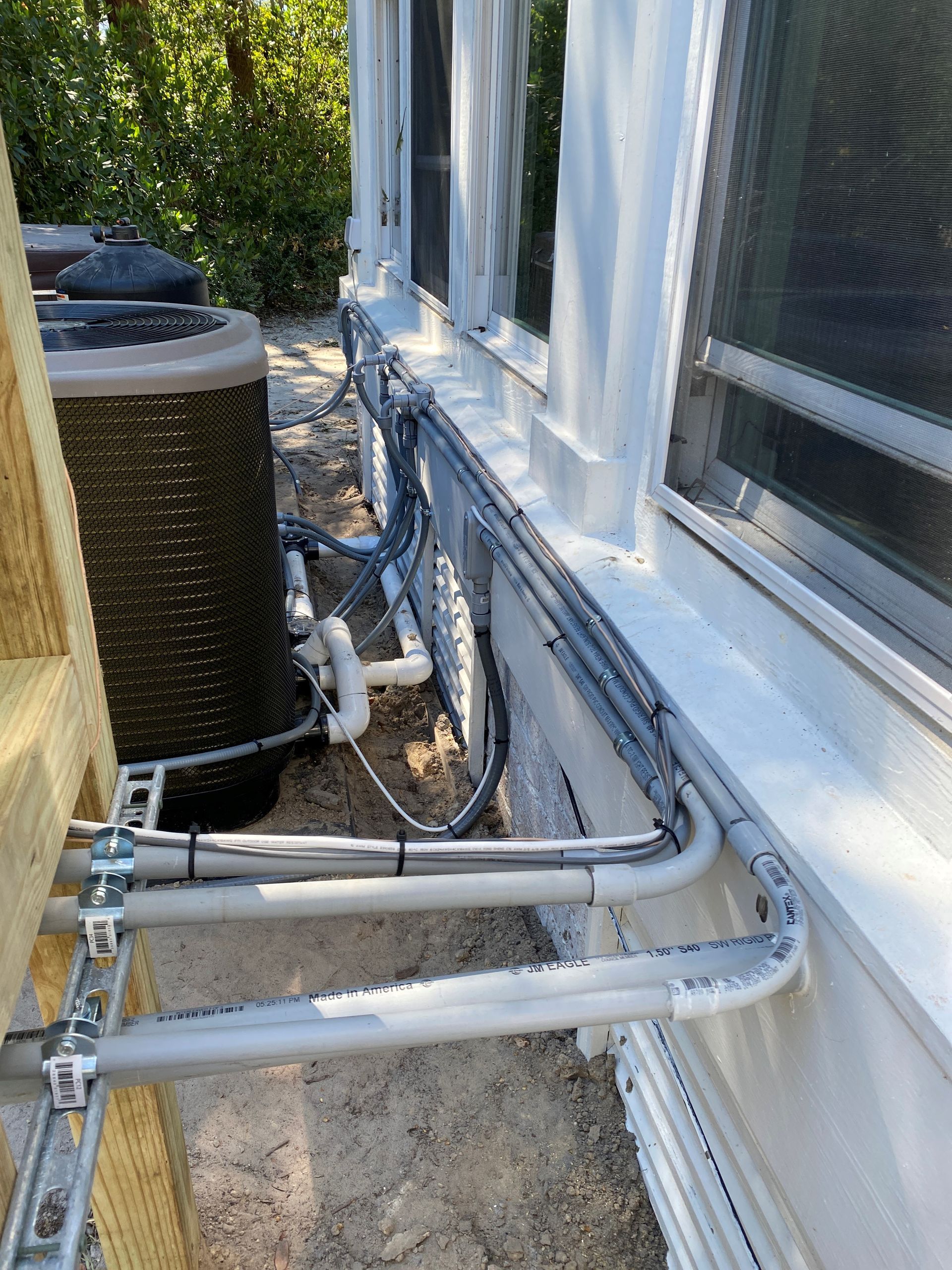 An air conditioner is being installed on the side of a house.