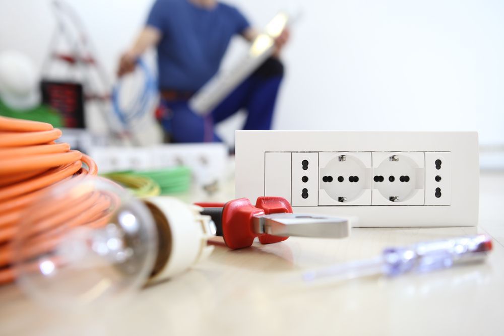 An electrician is working on a light fixture in the background