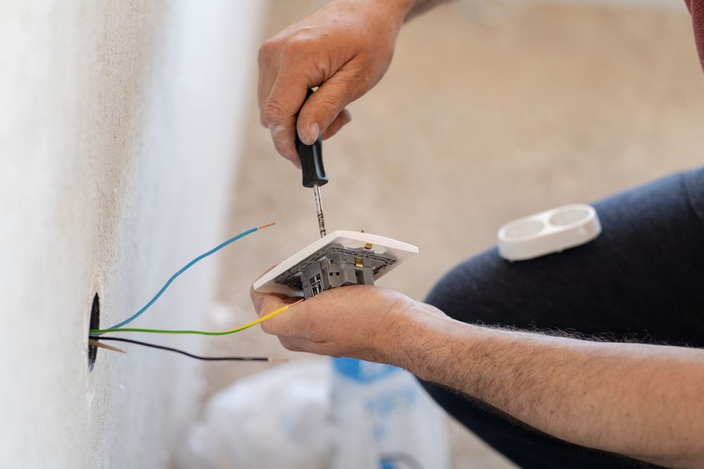 A man is installing a light switch on a wall.