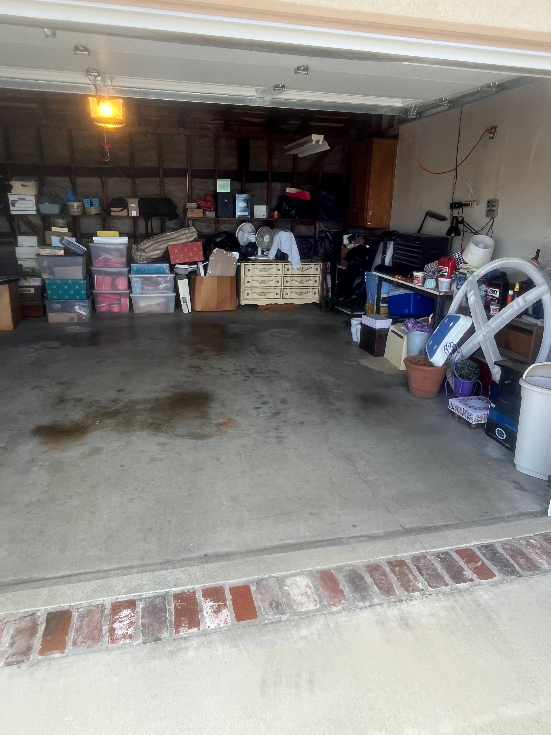 A cluttered garage filled with storage bins, boxes, and miscellaneous household items stacked on shelves and the floor.