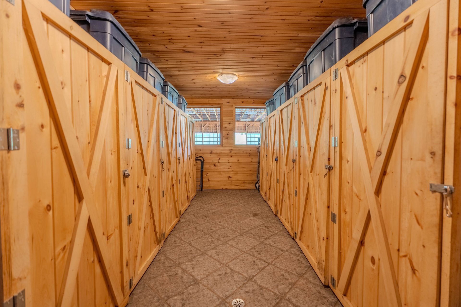A long hallway filled with wooden lockers in a barn.