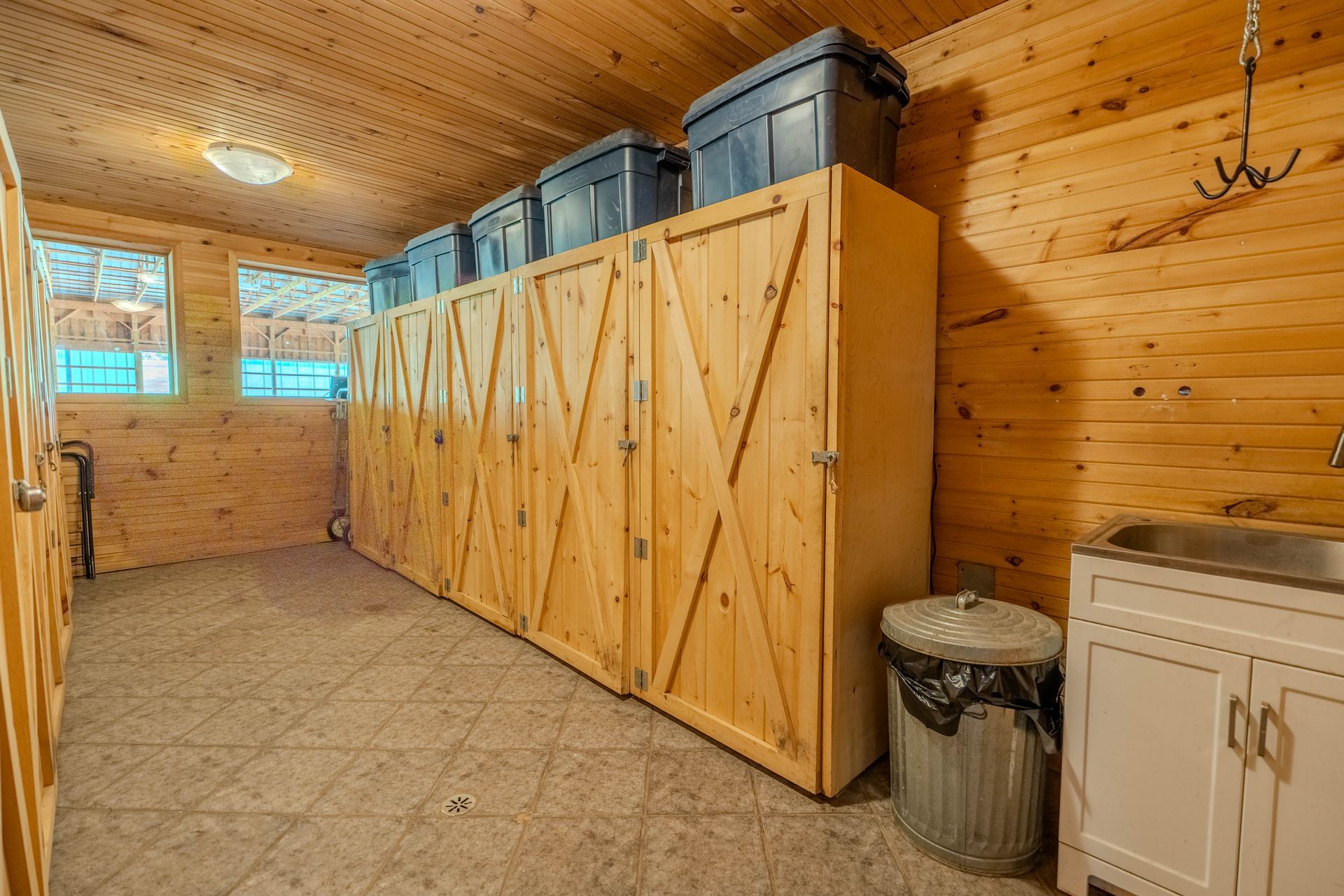 A wooden room with a sink and lots of storage boxes.