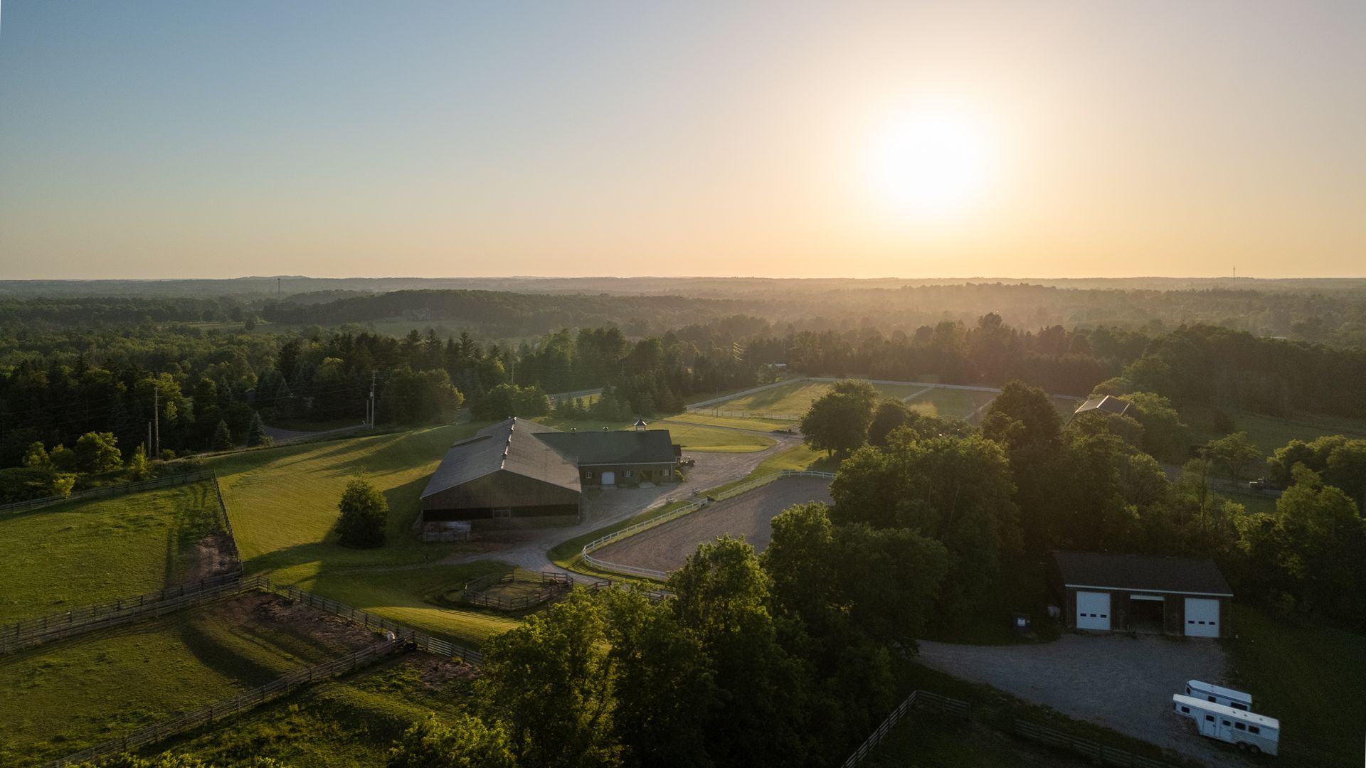 An aerial view of a farm with a sunset in the background.