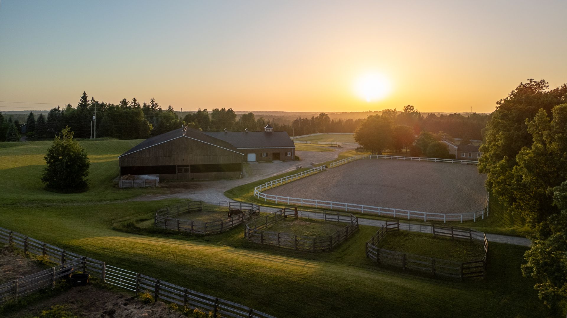 An aerial view of a horse farm at sunset.