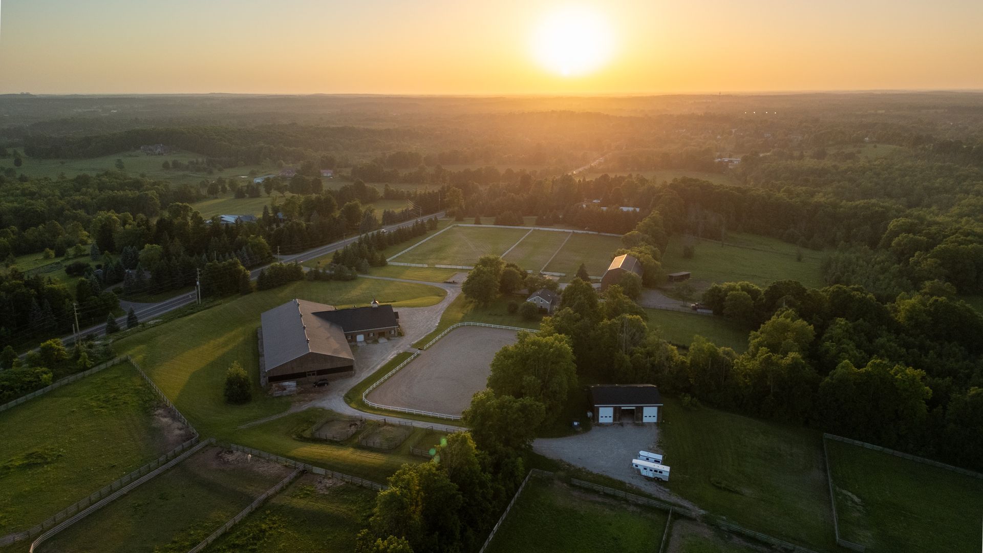 An aerial view of a farm with a sunset in the background.