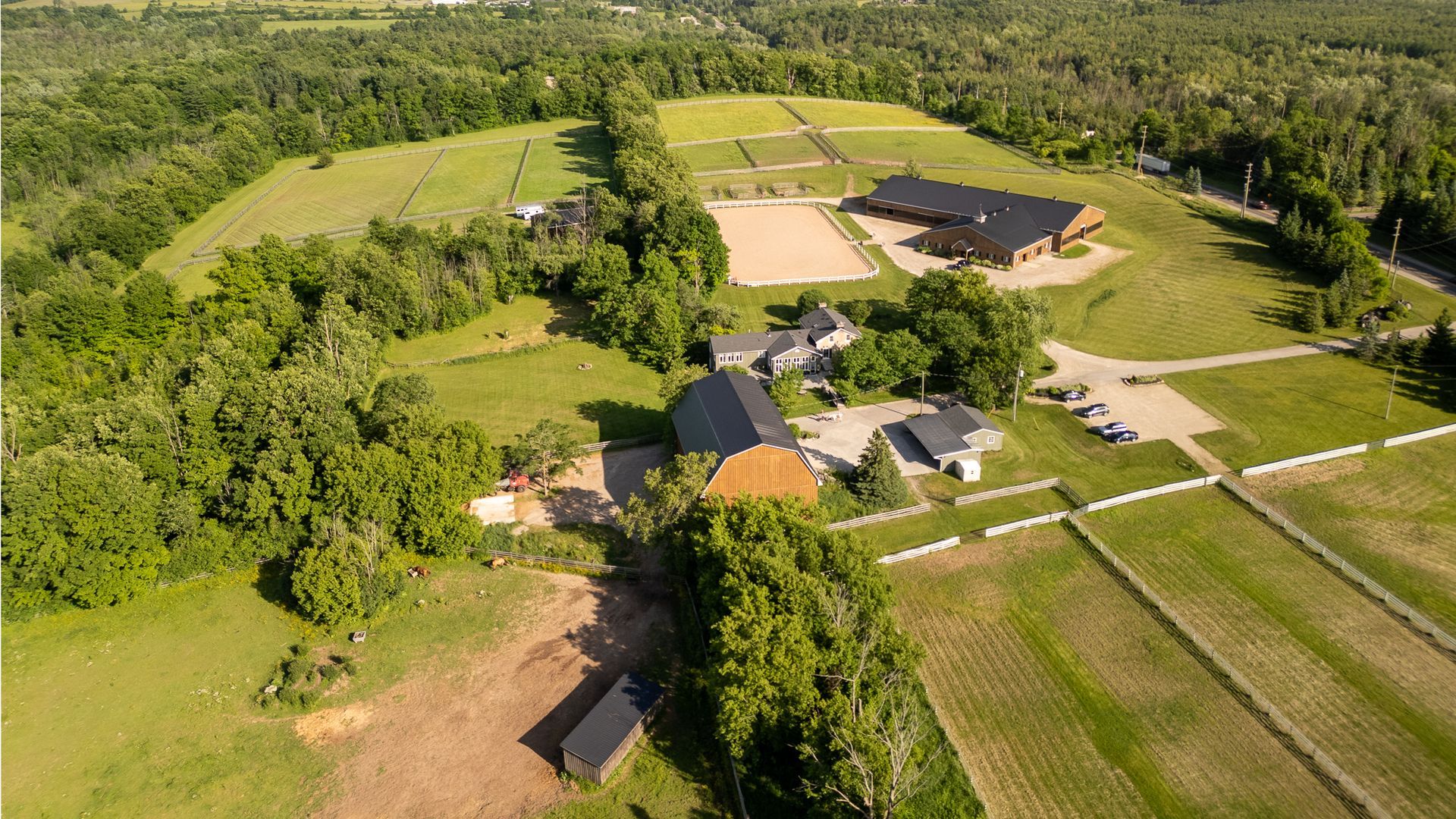 An aerial view of a large farm surrounded by trees and grass.