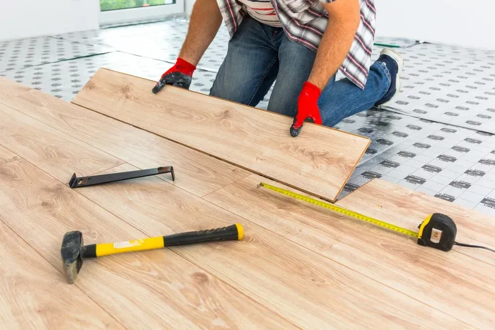 Person Installing Wood Flooring — Sly Bros in Woodburn, NSW
