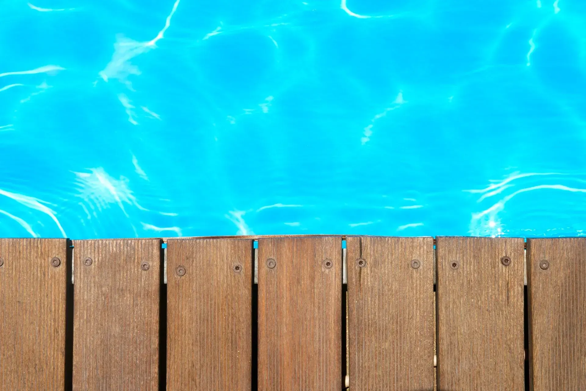 Wooden Deck Adjacent to a Bright Blue Swimming Pool — Sly Bros in Woodburn, NSW