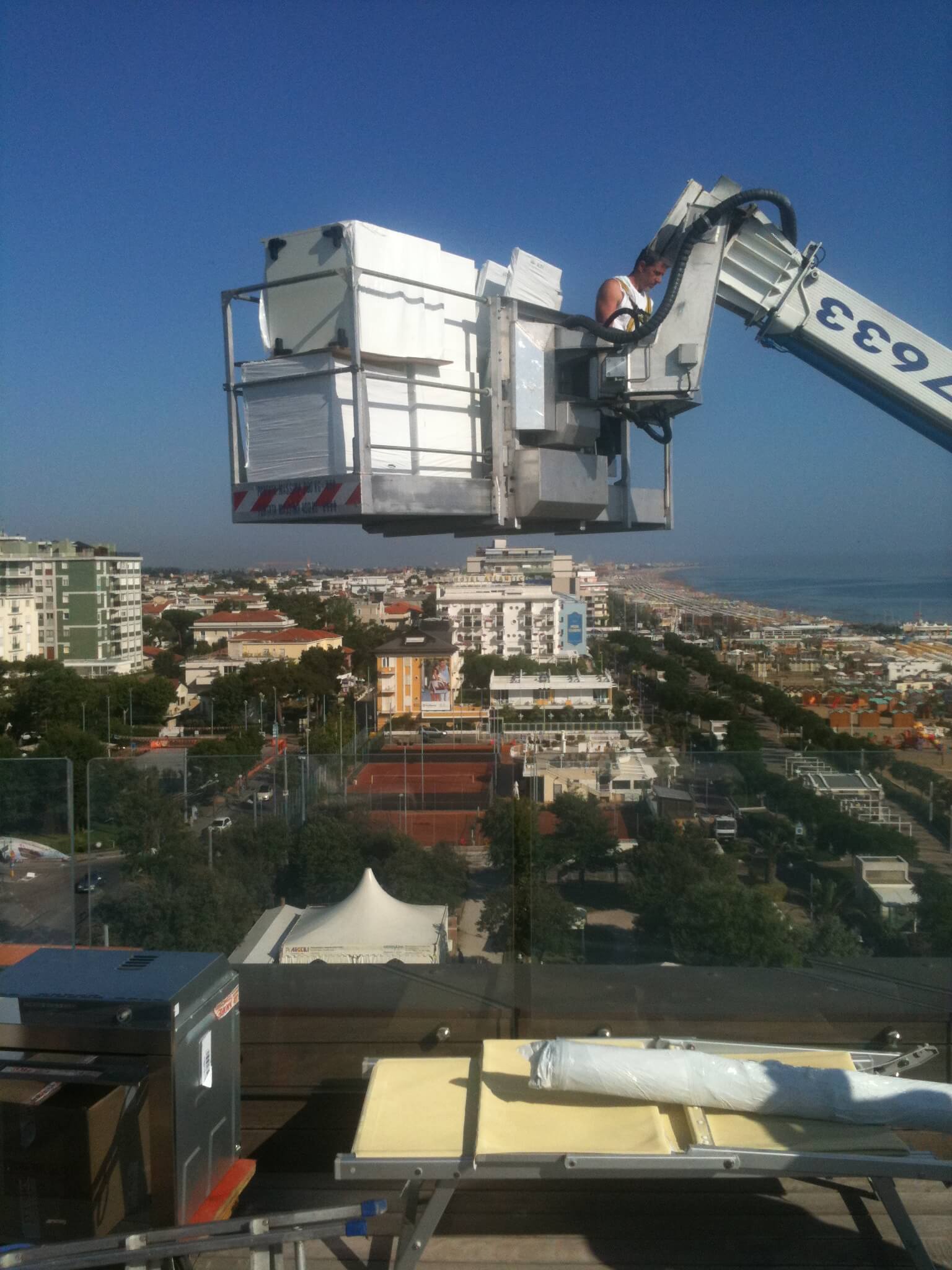 Un cestello di sollevamento aereo sopra una città costiera in una giornata di sole.